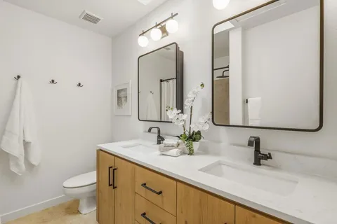 a bathroom with a double vanity sink toilet and mirror