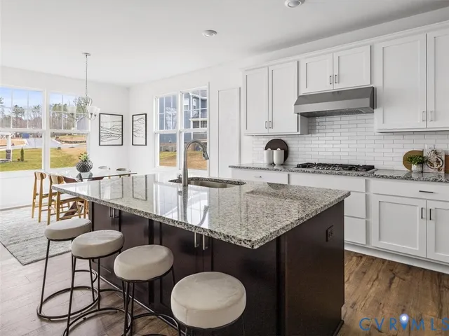 a kitchen with a sink a stove and white cabinets with wooden floor