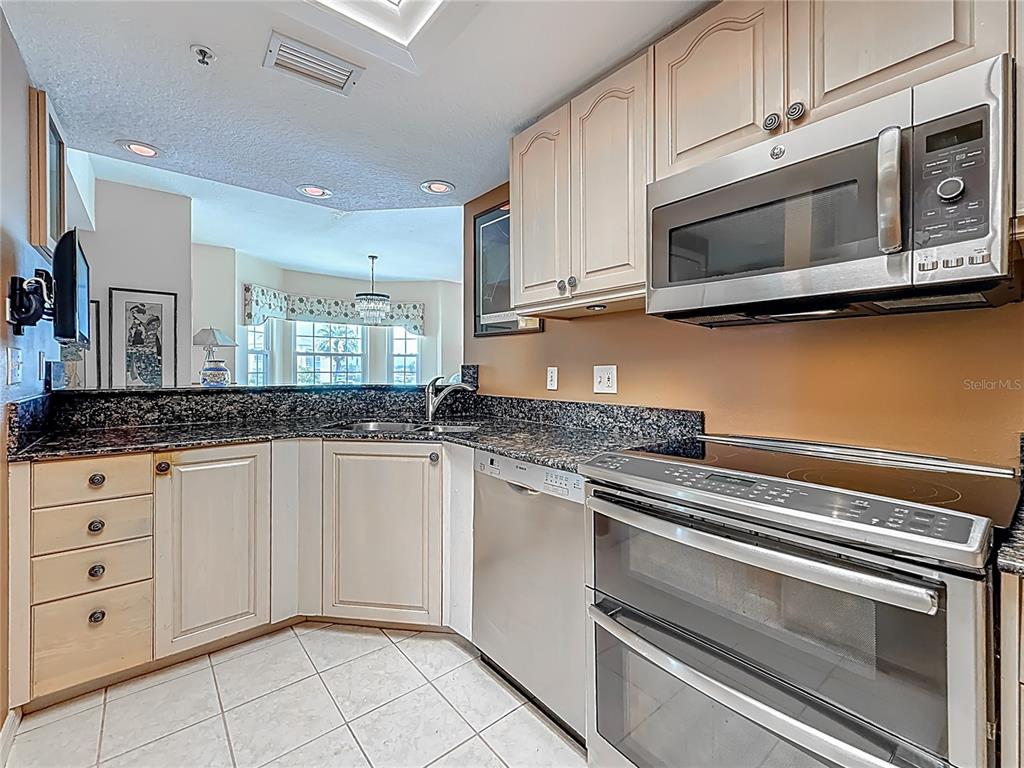 399 150th Avenue, Unit 317 Madeira Beach, FL 33708 - Photo 15 of 96 a kitchen with granite countertop white cabinets stainless steel appliances and a sink