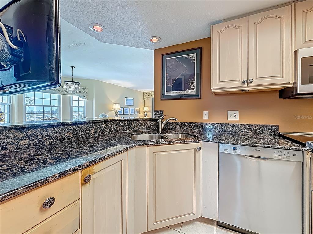 399 150th Avenue, Unit 317 Madeira Beach, FL 33708 - Photo 16 of 96 a kitchen with granite countertop white cabinets and sink