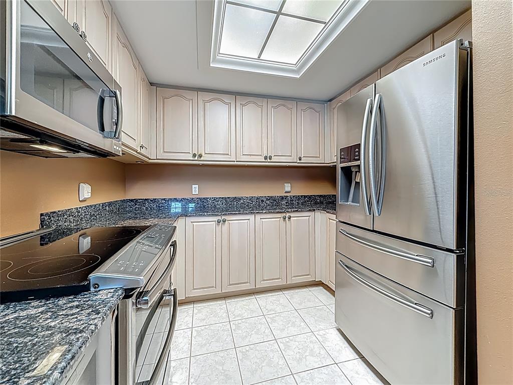 399 150th Avenue, Unit 317 Madeira Beach, FL 33708 - Photo 19 of 96 a kitchen with stainless steel appliances granite countertop a refrigerator a stove and a sink with cabinets