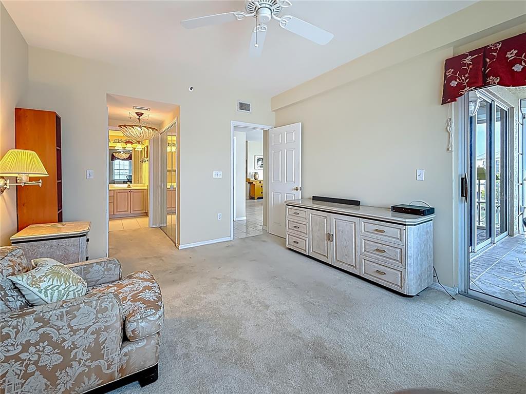 399 150th Avenue, Unit 317 Madeira Beach, FL 33708 - Photo 21 of 96 a spacious bedroom with a bed and a chandelier
