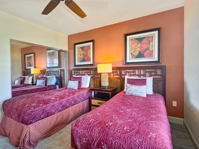 a bedroom with two beds and a large mirror on dresser