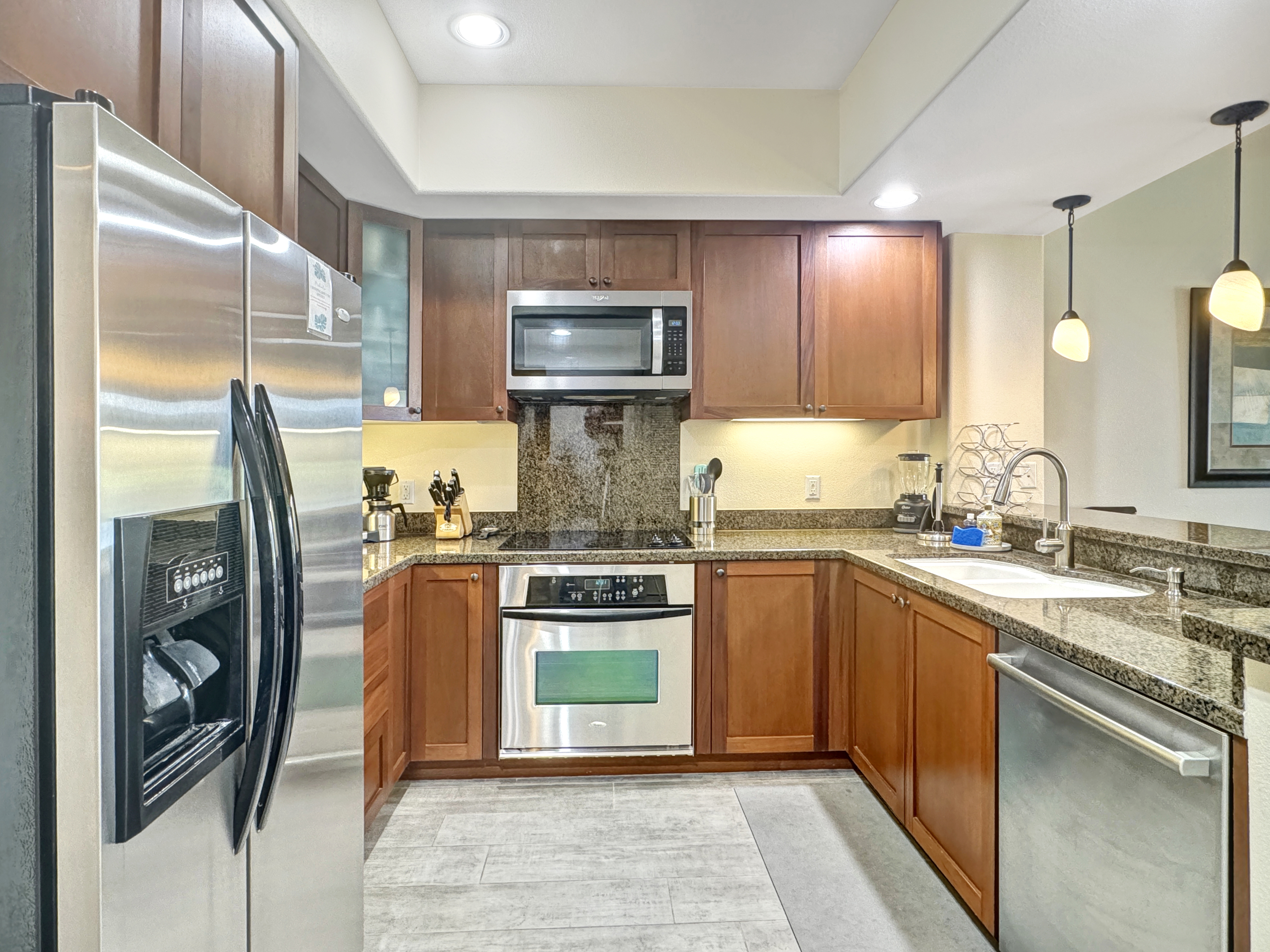 69-1033 Nawahine Place, Unit 9B Waikoloa, HI 96738 - Photo 5 of 24 a kitchen with stainless steel appliances granite countertop a refrigerator a stove and a sink