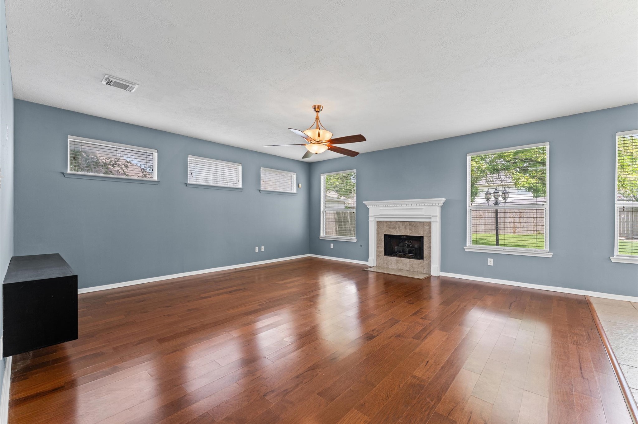 9202 State Walk Circle Houston, TX 77064 - Photo 6 of 25 This spacious living room features hardwood floors, a cozy fireplace, and abundant natural light from multiple windows.