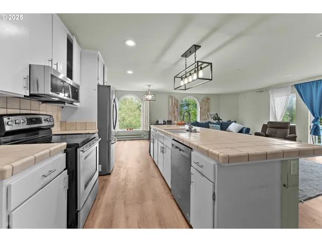 a kitchen with kitchen island granite countertop a sink a counter top space appliances and cabinets