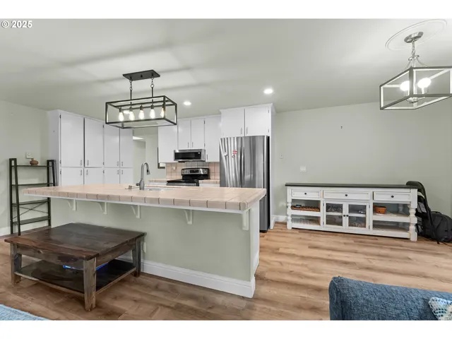 a kitchen with kitchen island stainless steel appliances a stove center island cabinets and wooden floor