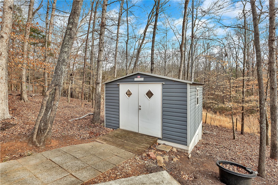 1432 Hunters Trail Anderson, SC 29625 - Photo 31 of 35 This outdoor shed offers additional storage amidst a natural, wooded landscape.