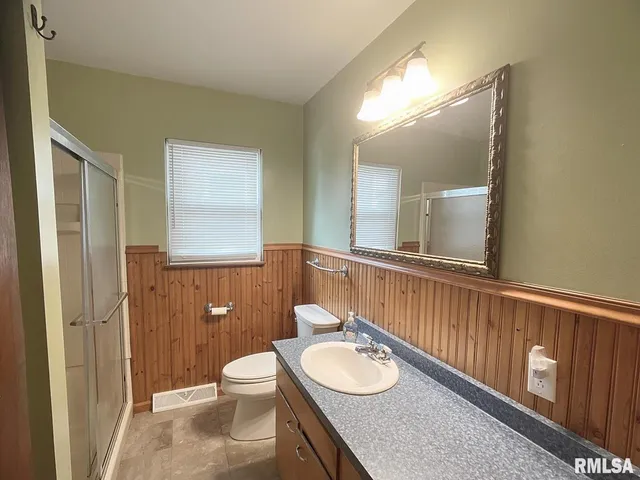 a bathroom with a toilet a sink a mirror and a shower