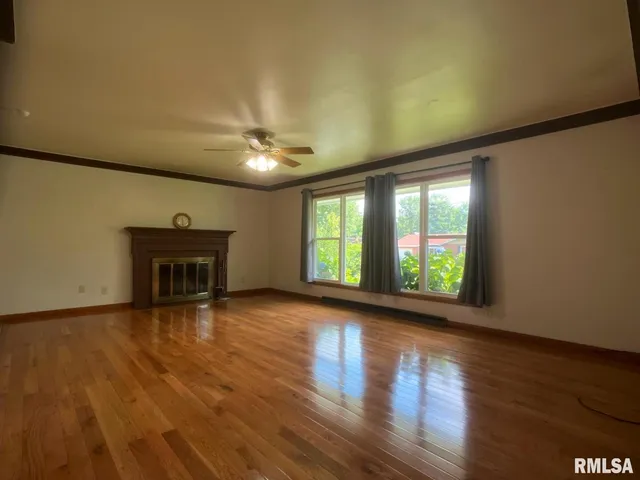 a view of empty room with wooden floor and fireplace