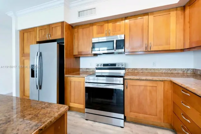 a kitchen with stainless steel appliances granite countertop a stove top oven a refrigerator and a sink with wooden floor