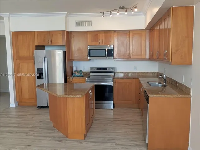 a kitchen with stainless steel appliances granite countertop a stove top oven a sink dishwasher a refrigerator and cabinets with wooden floor