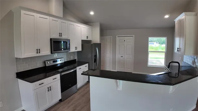 a kitchen with granite countertop a sink stove and refrigerator