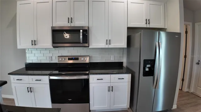 a kitchen with granite countertop white cabinets and stainless steel appliances