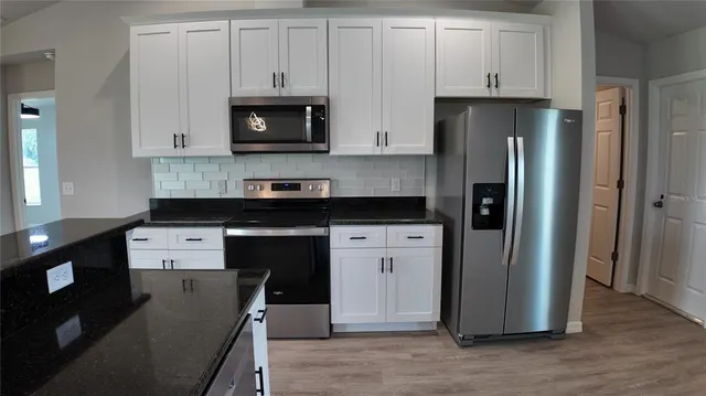 a kitchen with a refrigerator stove and white cabinets