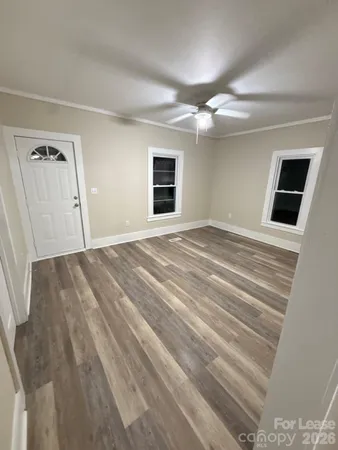 a view of empty room with wooden floor and fan