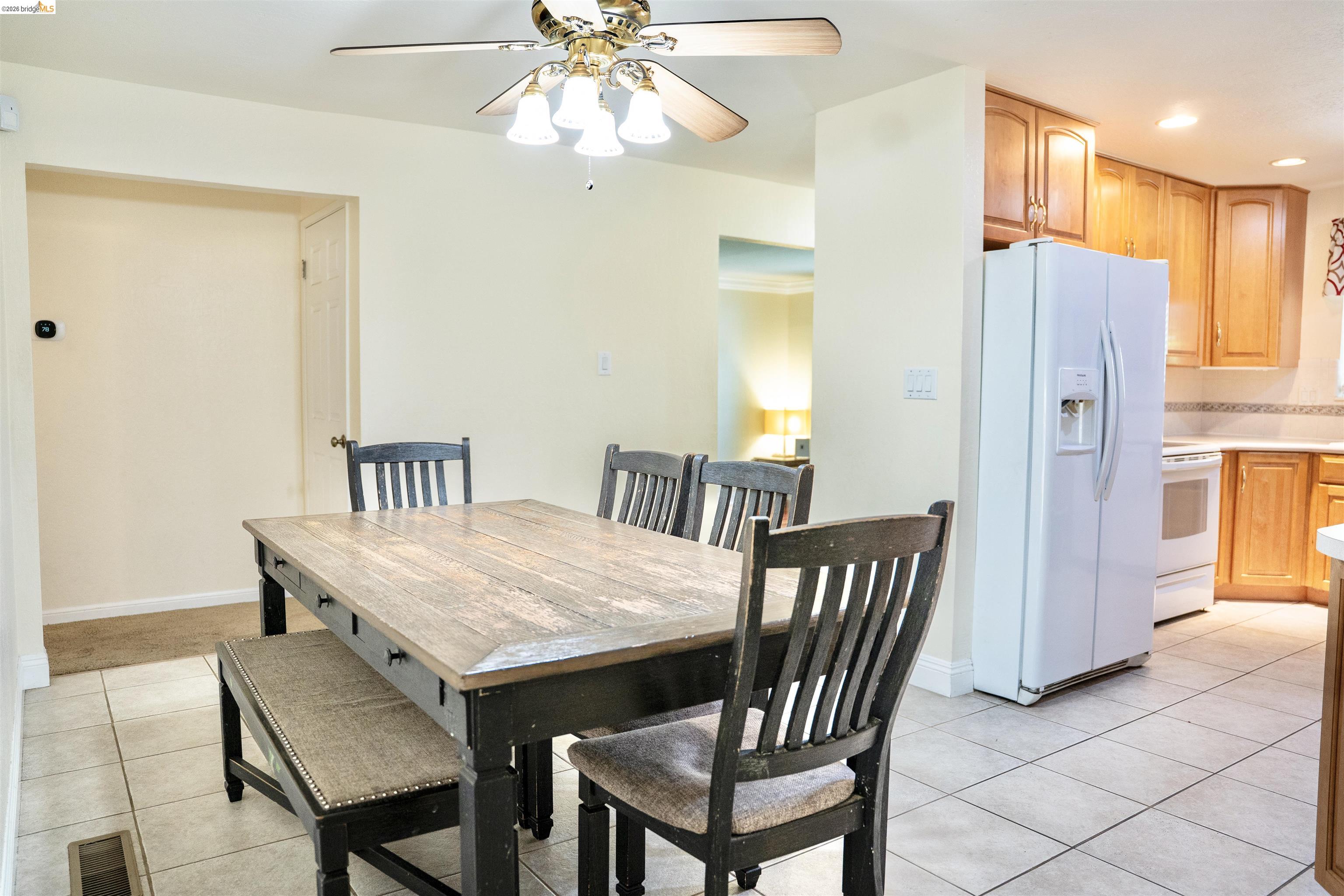 3513 Rio Grande Drive Antioch, CA 94509 - Photo 12 of 22 Dining area featuring a ceiling fan with light kit, tile flooring, and a kitchen with wood cabinetry, light countertops, and tile backsplash