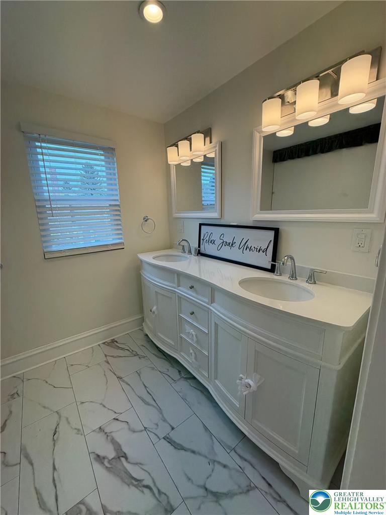 5111 Vera Cruz Road Emmaus, PA 18049 - Photo 29 of 44 A spacious double vanity and polished marble-look tile floors define this updated bathroom.