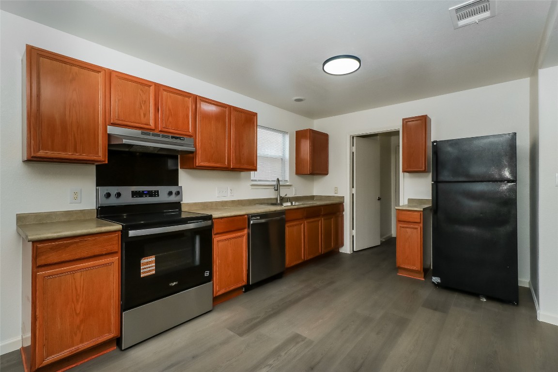 7012 Doyal Drive Austin, TX 78747 - Photo 9 of 17 a kitchen with stainless steel appliances granite countertop a stove a sink dishwasher a refrigerator and a microwave oven
