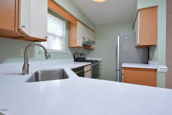 a kitchen with granite countertop a sink a stove and a wooden cabinets