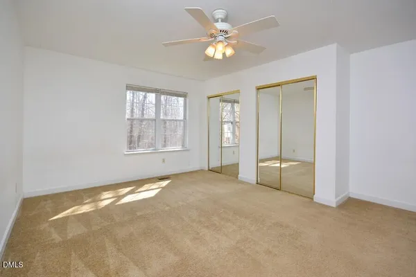 an empty room with windows and ceiling fan