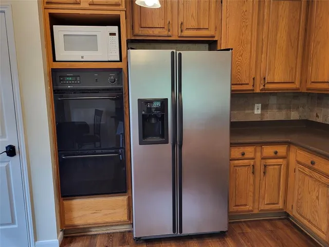a refrigerator freezer sitting in a kitchen with stainless steel appliances wooden floor and cabinets