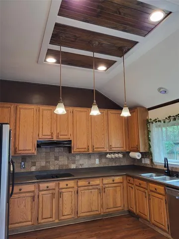 a kitchen with stainless steel appliances granite countertop a sink a stove and a wooden cabinets