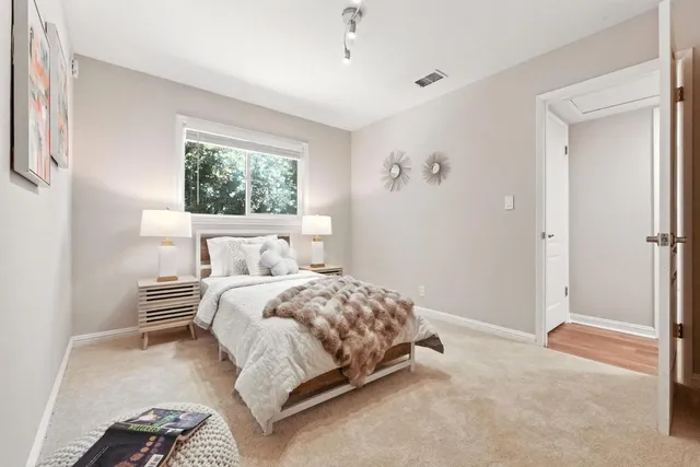 a view of a white house with a big yard plants and large trees
