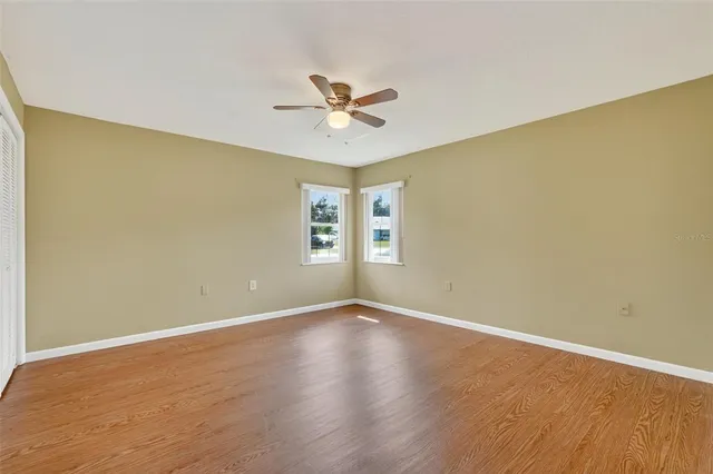 a view of an empty room with a window and wooden floor