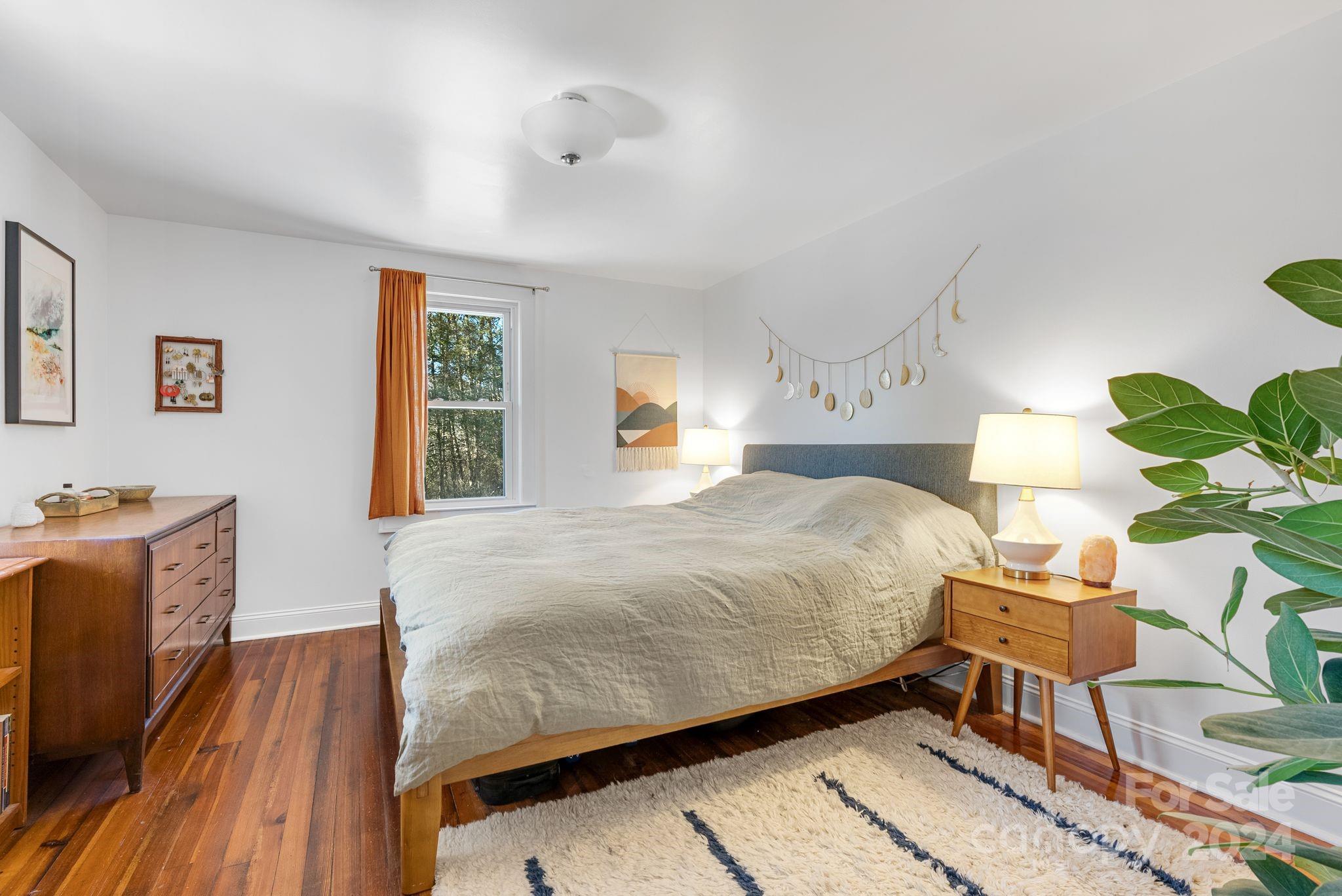 608 Barnard Road Marshall, NC 28753 - Photo 11 of 23 a bedroom with a bed potted plant on dresser and a wooden floor