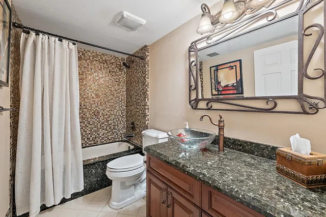 a bathroom with a granite countertop sink mirror vanity and toilet