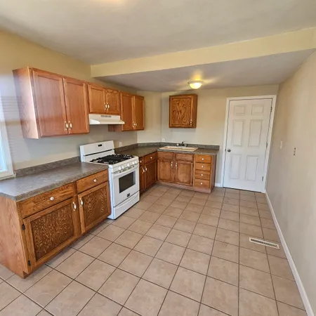 a kitchen with granite countertop a stove top oven cabinetry and garage