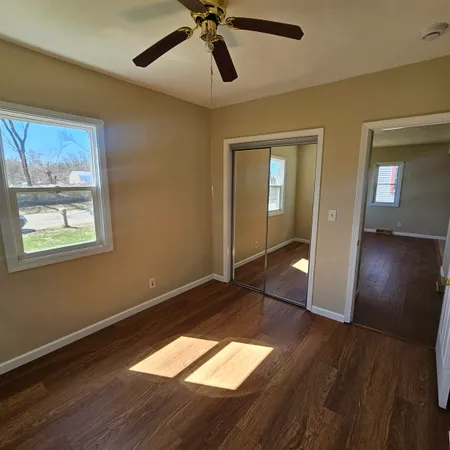 a view of empty room with wooden floor and fan