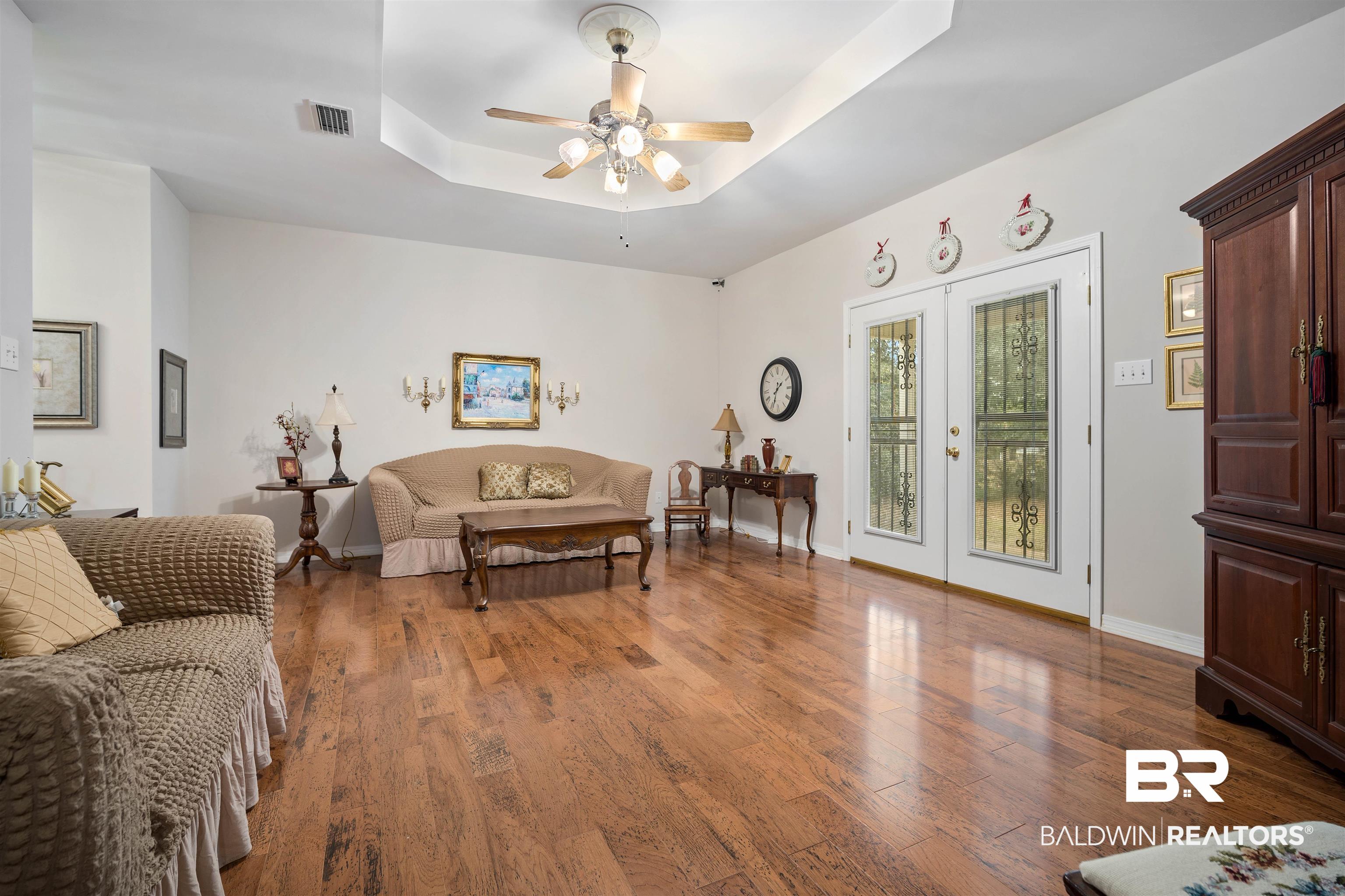 7419 Pake Road Saraland, AL 36571 - Photo 5 of 27 Living room with french doors, a tray ceiling, ceiling fan, and wood-type flooring