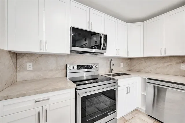 a kitchen with white cabinets and stainless steel appliances