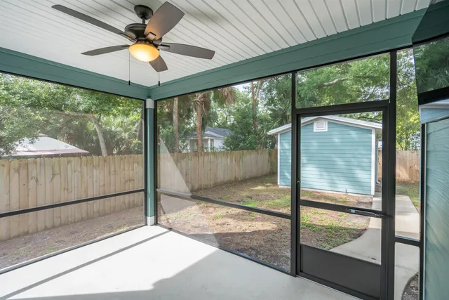 a living room with a floor to ceiling window and a ceiling fan