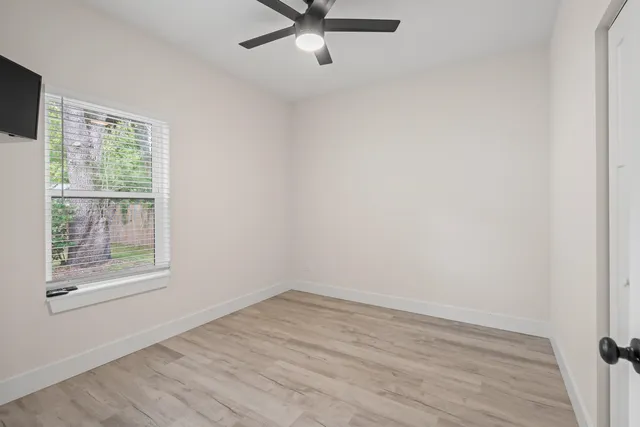 an empty room with a window and a ceiling fan