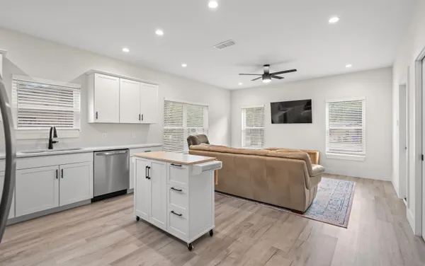 a large white kitchen with a window wooden floor and a sink
