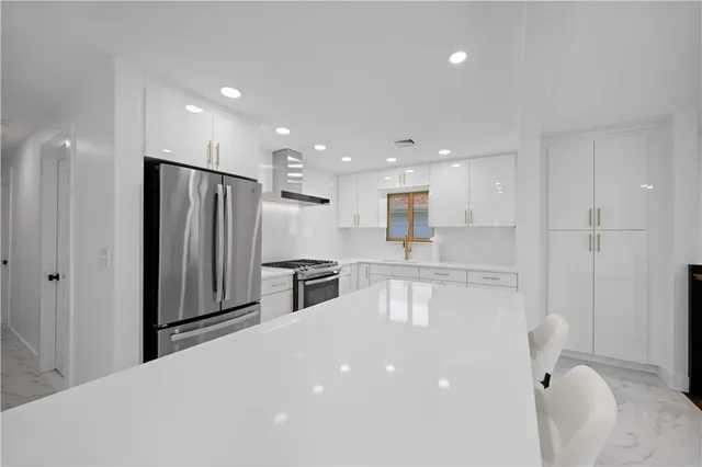 a kitchen with kitchen island white cabinets and stainless steel appliances