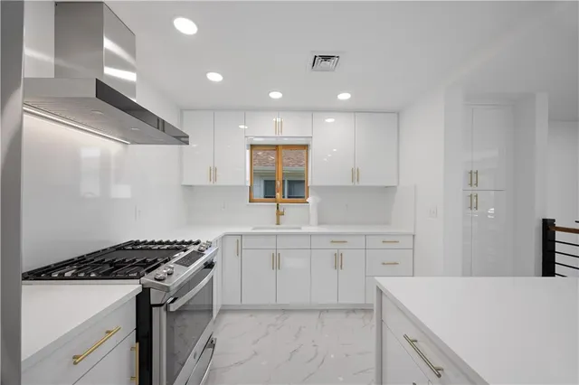 a large white room with a large window and stainless steel appliances