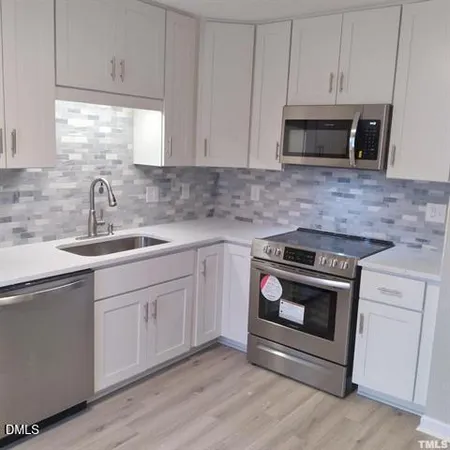 a kitchen with white cabinets stainless steel appliances and sink