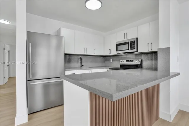 a kitchen with stainless steel appliances granite countertop a refrigerator a sink a stove a microwave and white cabinets