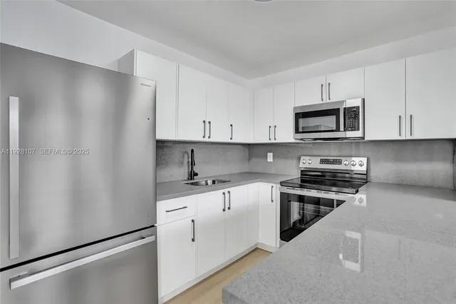 a kitchen with granite countertop white cabinets and stainless steel appliances