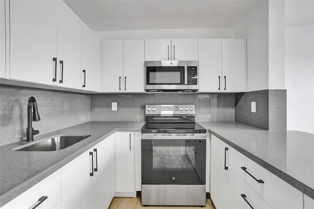 a kitchen with cabinets appliances a sink and a counter top