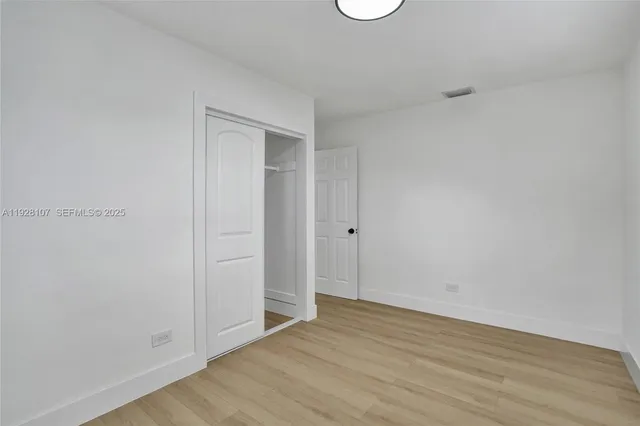 an empty room with wooden floor and window