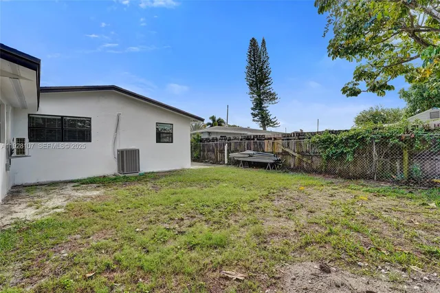 a backyard of a house with plants and large tree