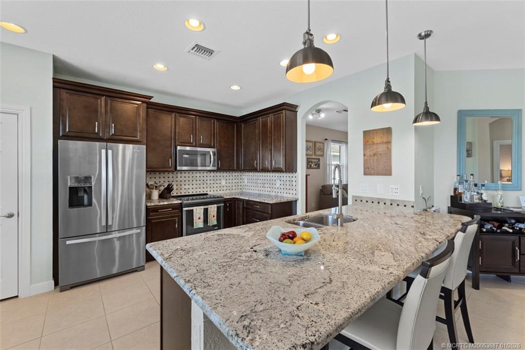 1171 Southeast Kirk Street Stuart, FL 34997 - Photo 12 of 47 a kitchen with stainless steel appliances granite countertop a sink a stove and refrigerator