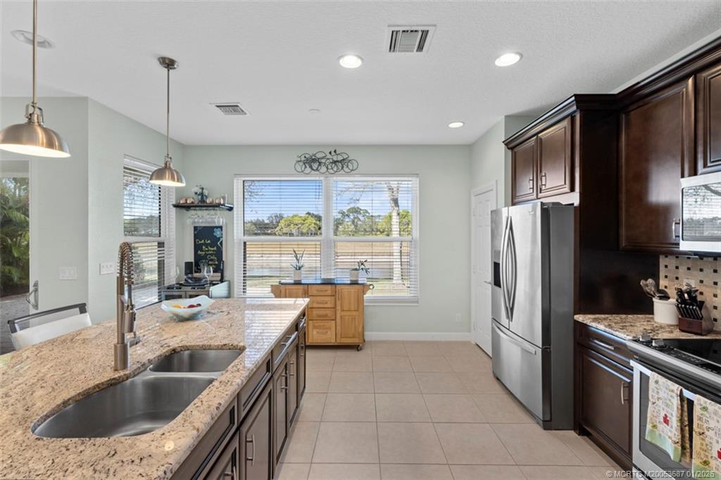 1171 Southeast Kirk Street Stuart, FL 34997 - Photo 13 of 47 a kitchen with stainless steel appliances granite countertop a sink stove and refrigerator