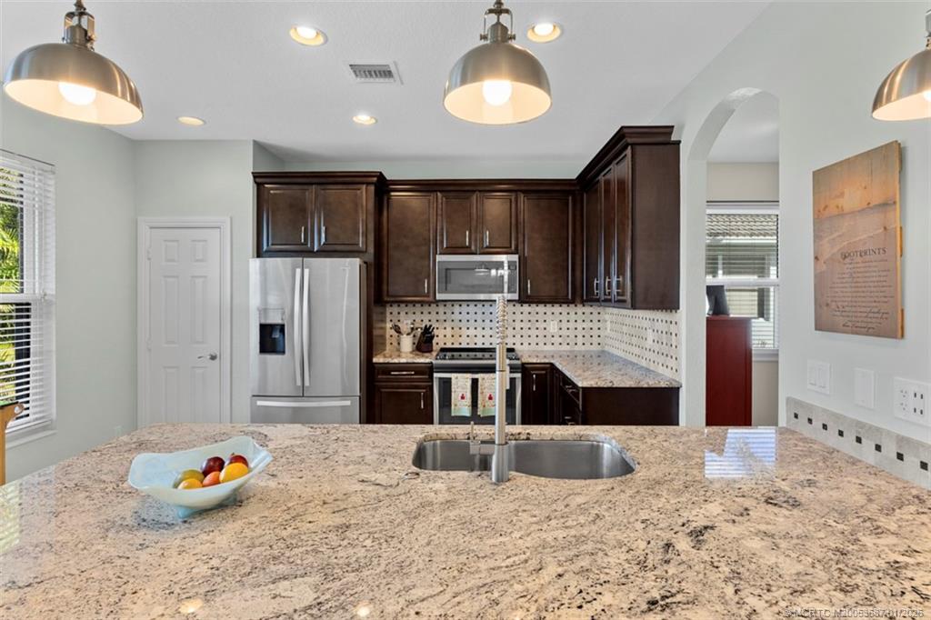 1171 Southeast Kirk Street Stuart, FL 34997 - Photo 14 of 47 a kitchen with stainless steel appliances kitchen island granite countertop a stove and a sink with cabinets