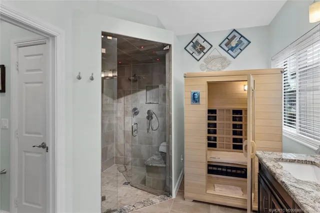 a bathroom with a granite countertop sink a mirror a shower and a window